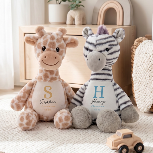 Two personalized plush stuffed animals, a giraffe  and a zebra, sitting side by side on a cream rug in a styled nursery setting.